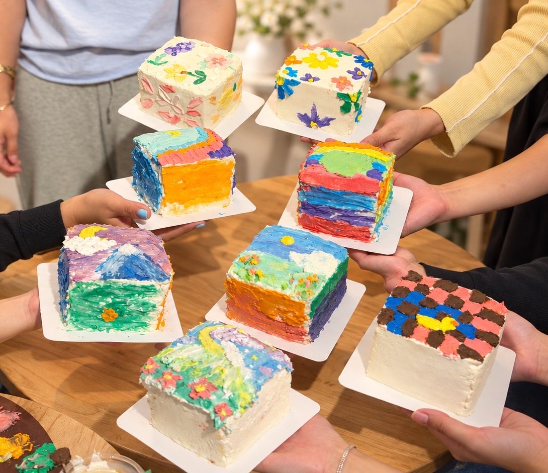 Eight painted square cakes held up by a class group